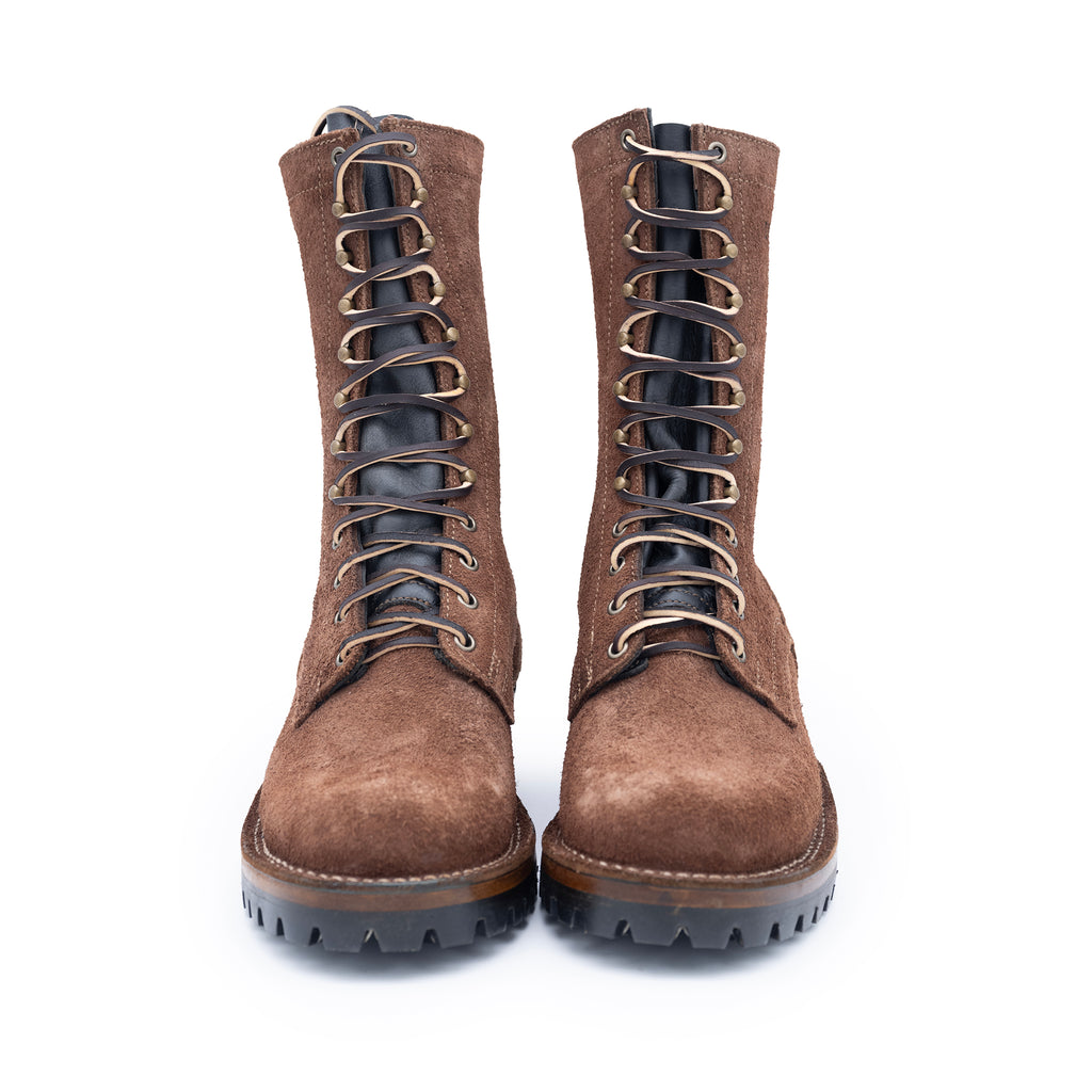 Pair of brown suede boots with black soles on a white background