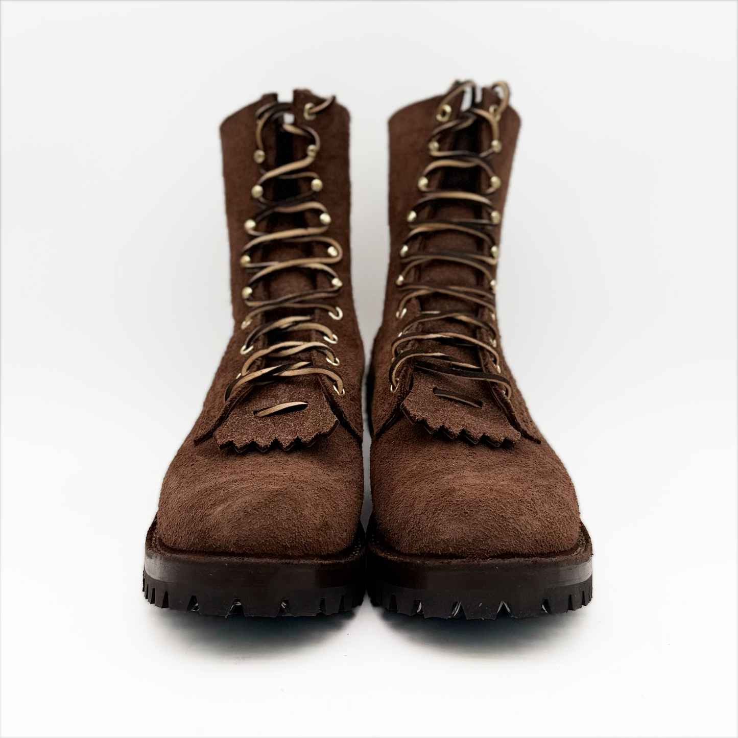 Pair of brown suede boots with black soles on a white background