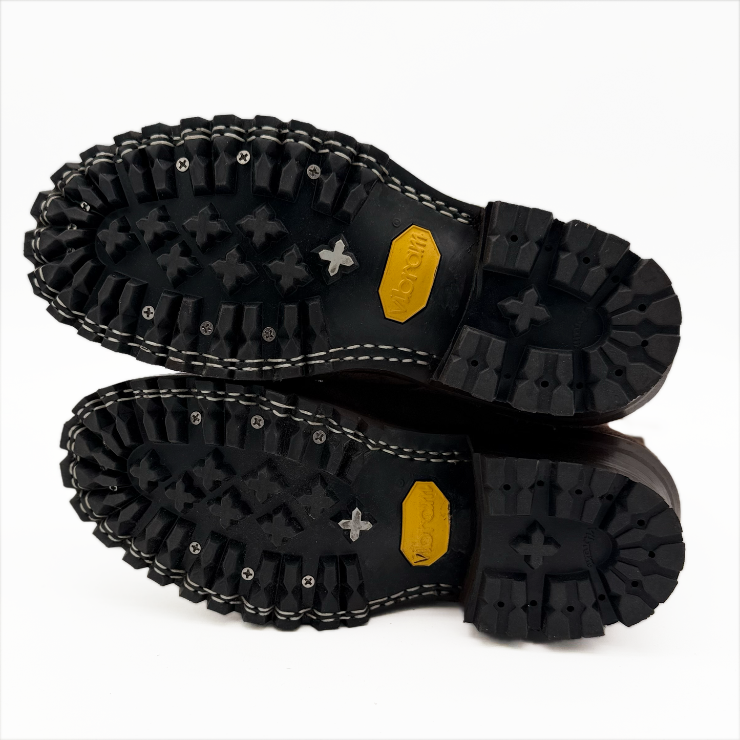 Close-up of black boot soles with a Vibram brand logo on a white background