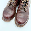 Pair of brown leather boots with BROWN LEATHER laces on a light gray background