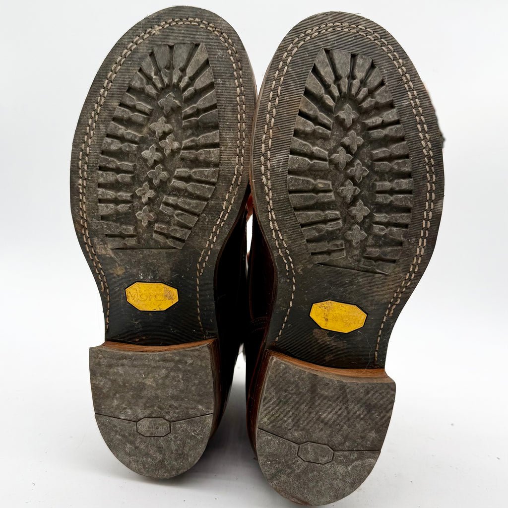 Close-up of the soles of brown leather shoes with yellow accents on a white background