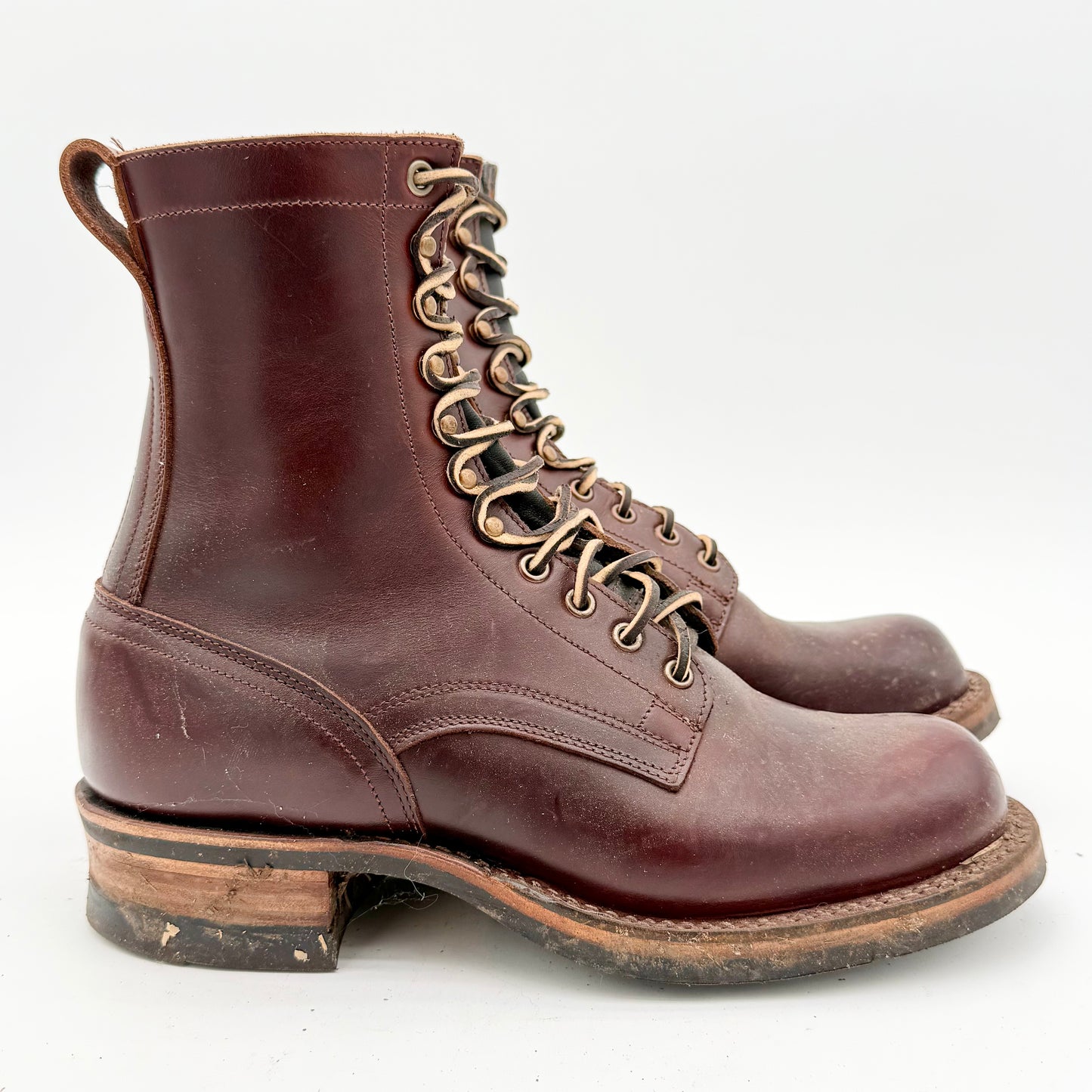 Pair of brown leather boots with worn soles on a white background