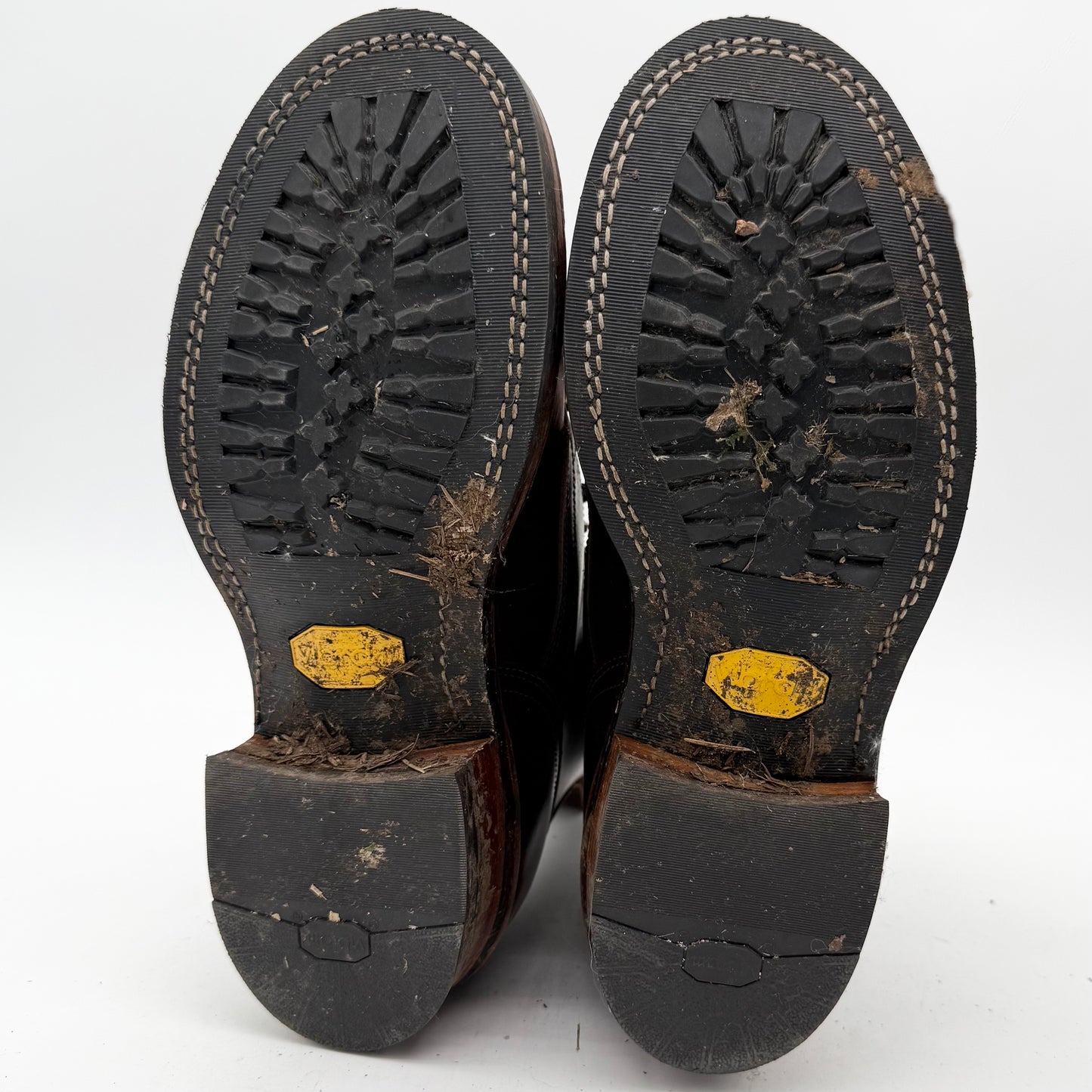 Close-up of worn black shoes with yellow labels on a white background