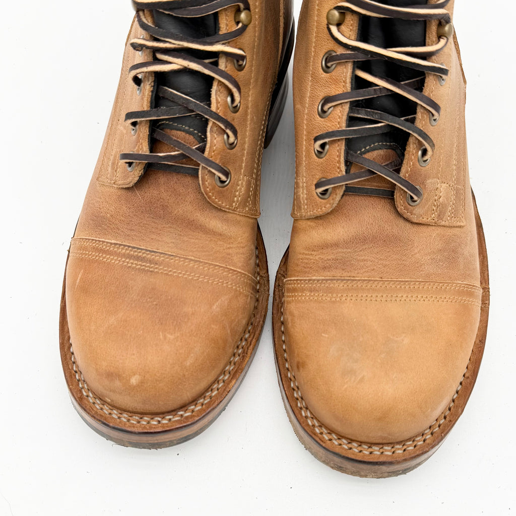 Pair of brown leather boots with black laces on a white background