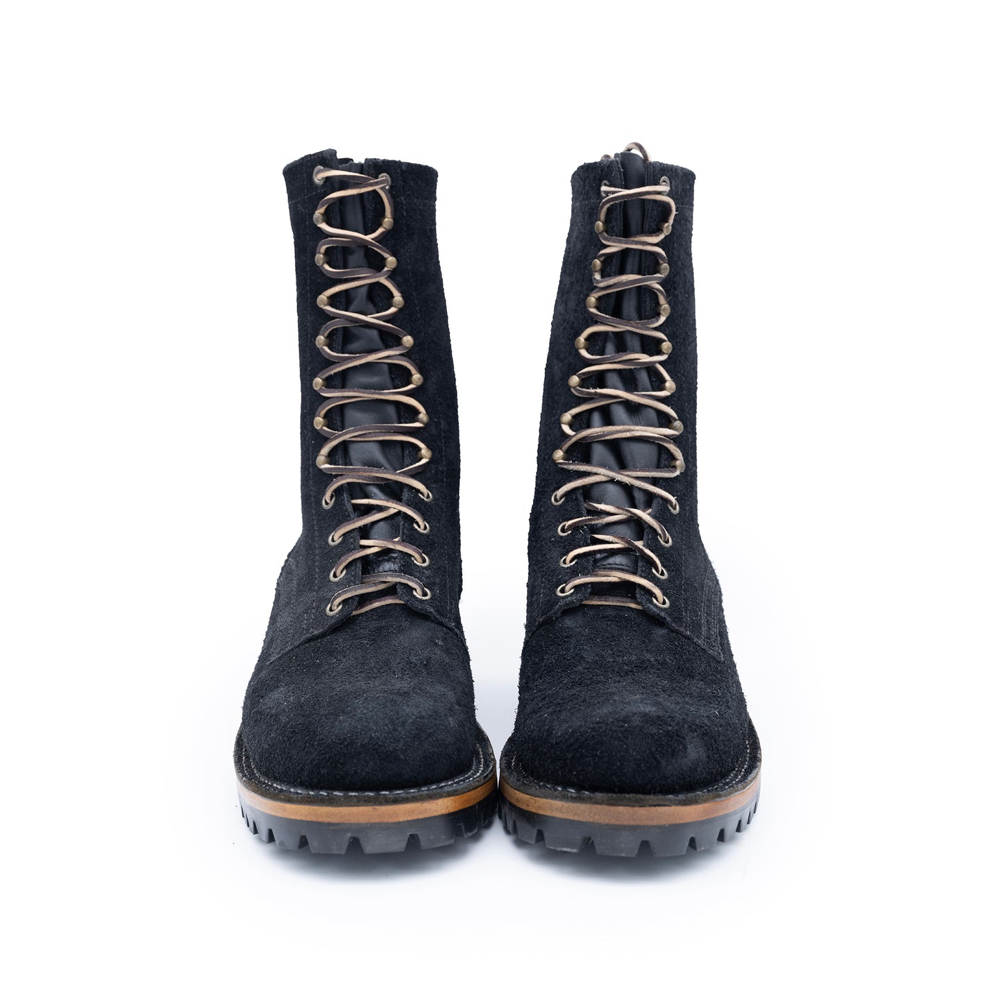 Pair of black suede boots with brown laces on a white background