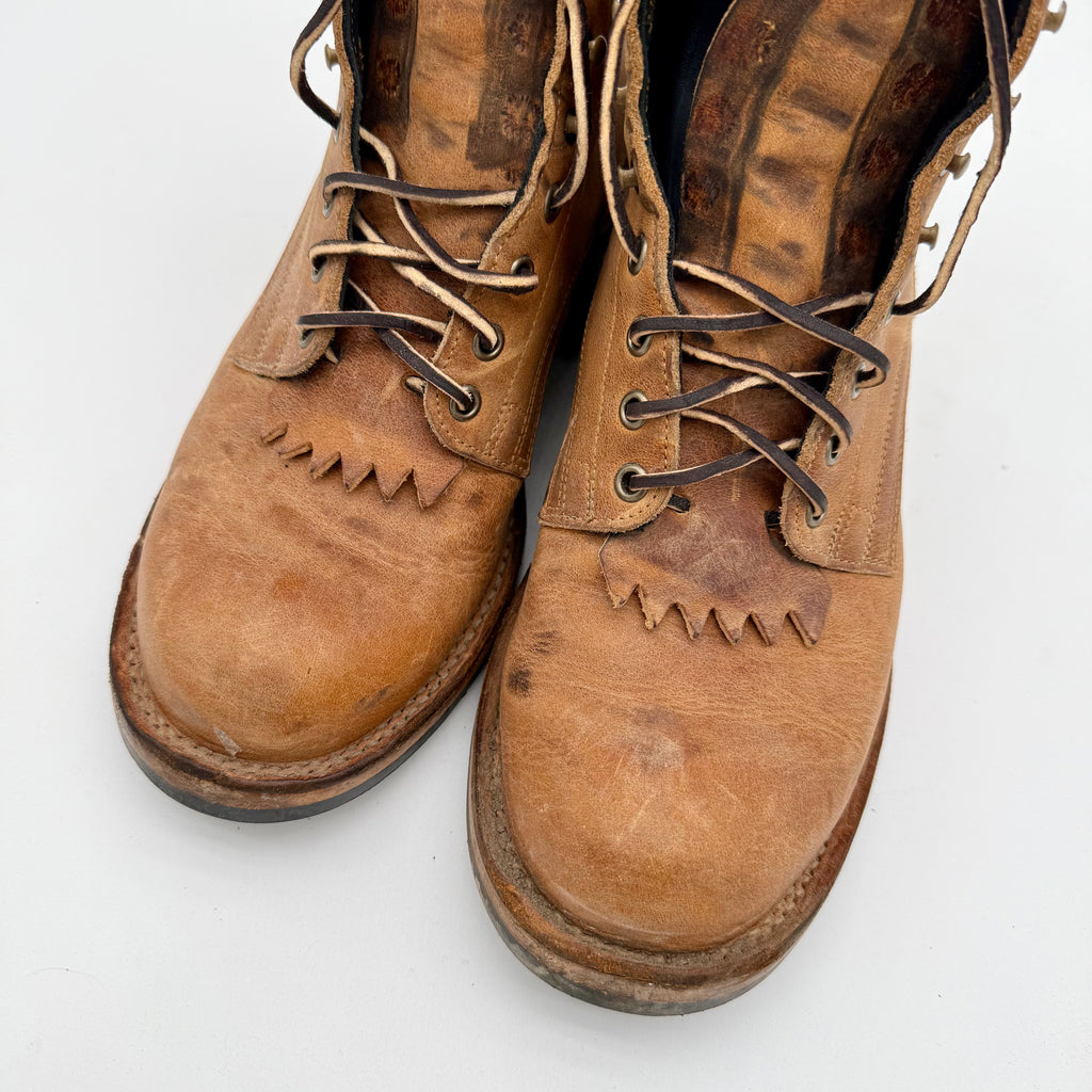 Pair of worn brown leather boots on a white background
